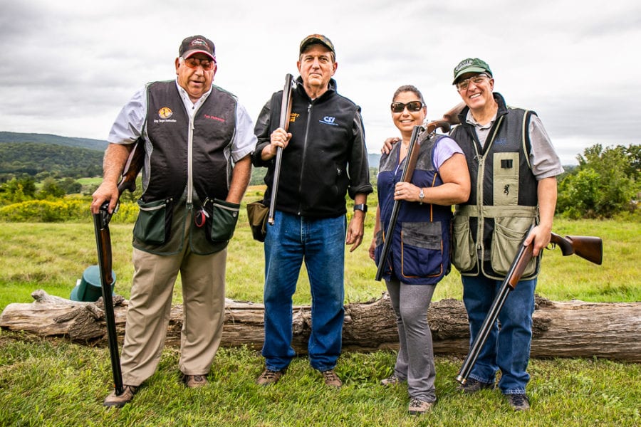Four shotgun shooters posing in grassy field