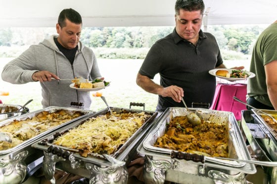 People serving themselves at buffet with chafing dishes