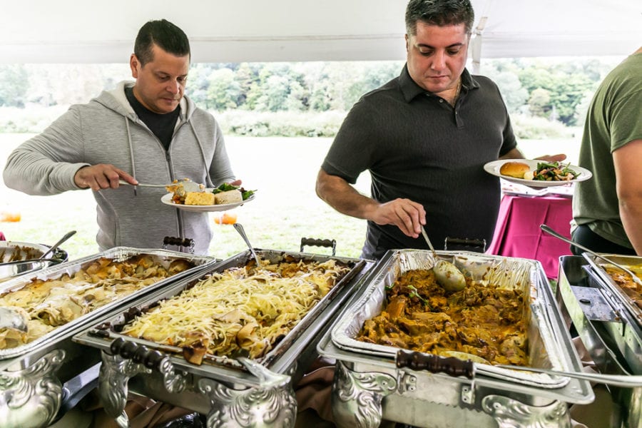 People serving themselves at buffet with chafing dishes