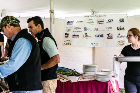 People serving and taking food at buffet tent