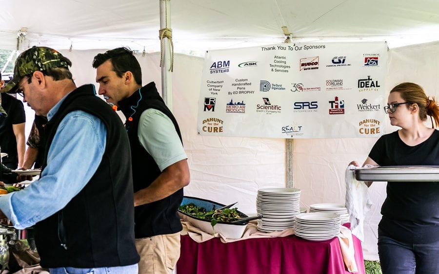 People serving and taking food at buffet tent