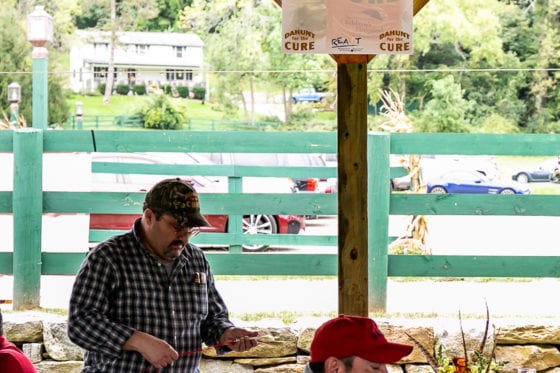 Two men at outdoor pavilion beneath sponsor sign