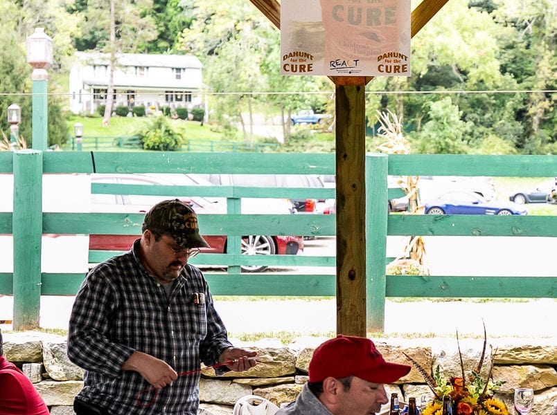 Two men at outdoor pavilion beneath sponsor sign
