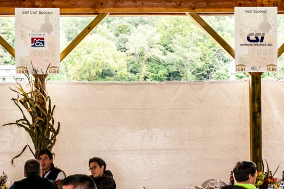 People seated under pavilion with sponsor banners