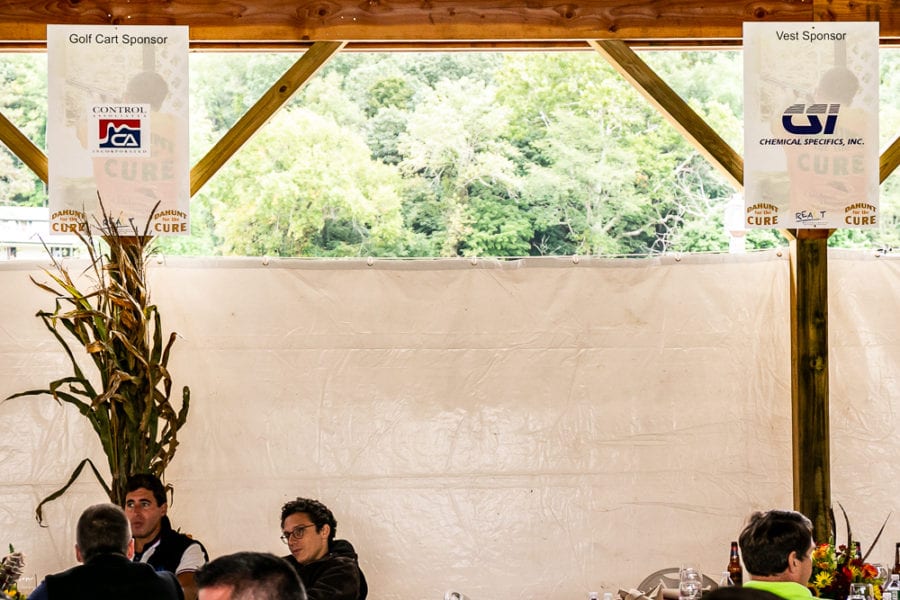 People seated under pavilion with sponsor banners