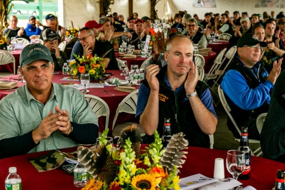 Audience applauding at banquet with floral centerpieces
