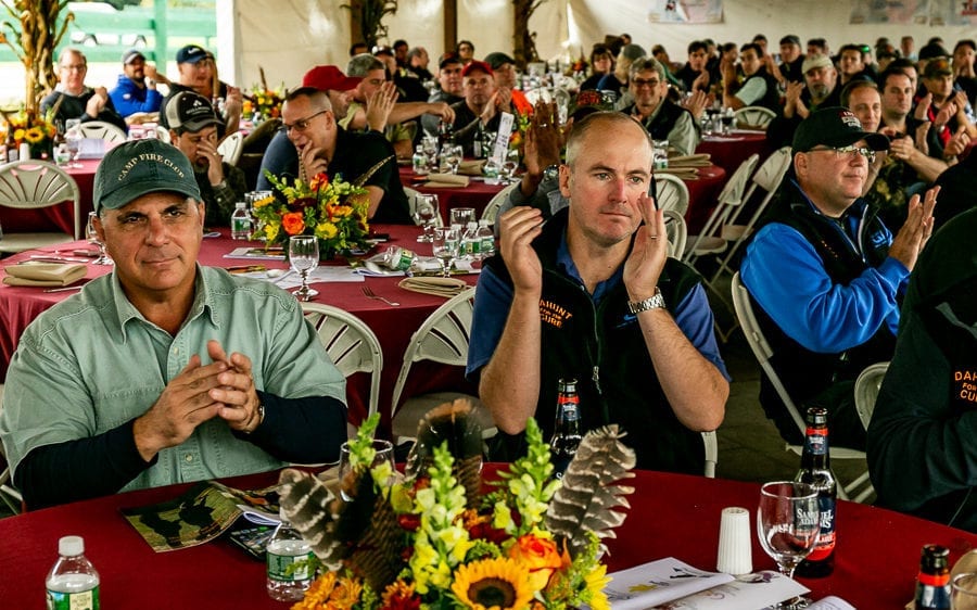 Audience applauding at banquet with floral centerpieces