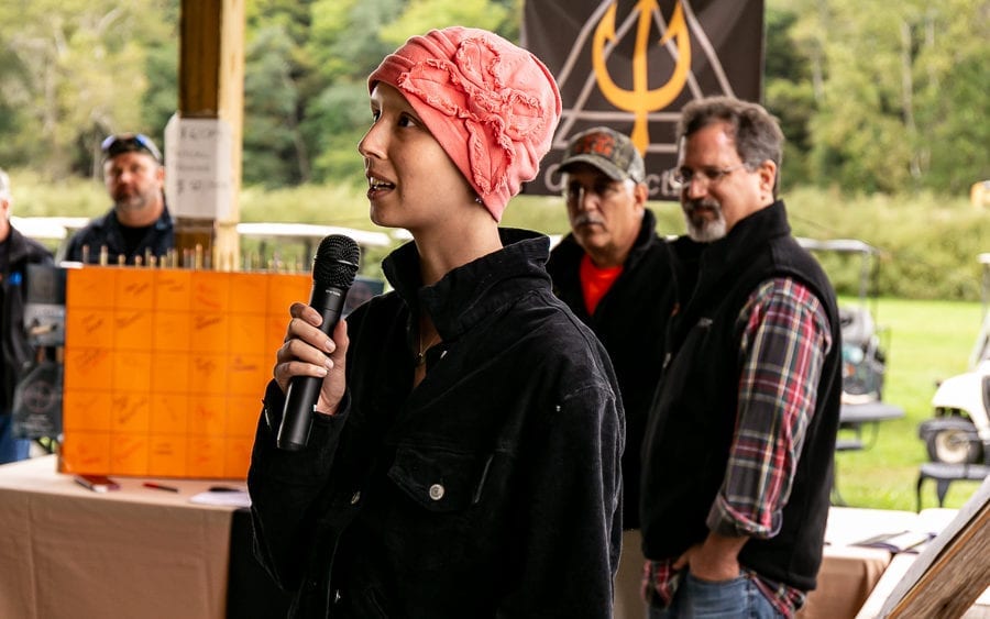 Person speaking into microphone with pink head covering