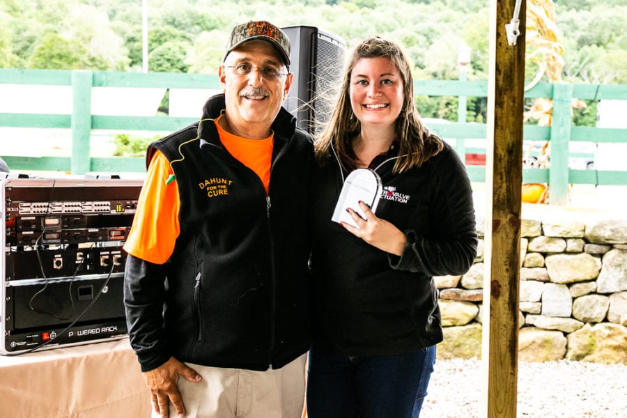 Two smiling people holding award outdoors
