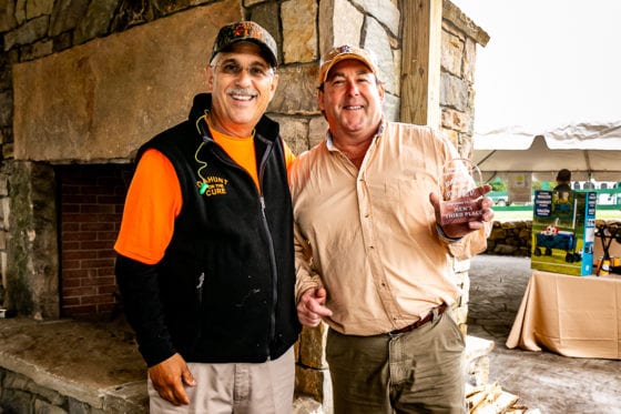 Two men with trophy at outdoor fireplace