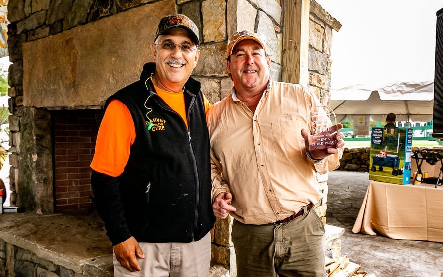 Two men with trophy at outdoor fireplace