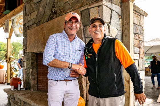 Two men smiling and shaking hands outdoors