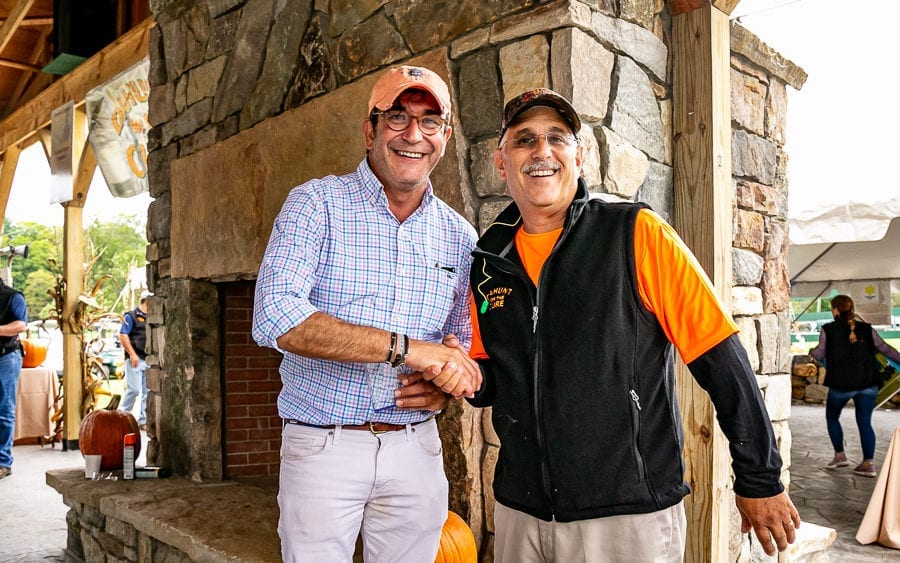 Two men smiling and shaking hands outdoors