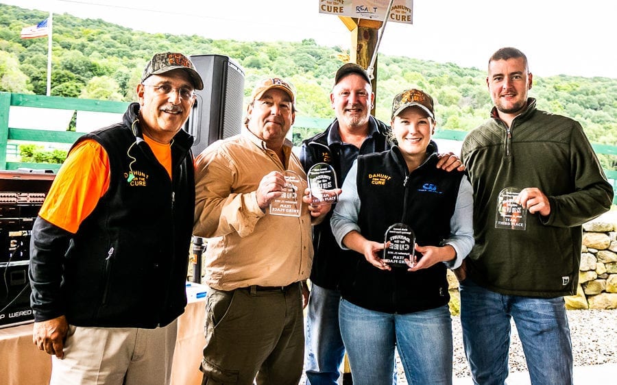 Five people holding awards outdoors