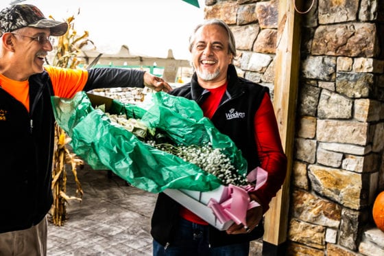 Two men smiling, holding large wrapped bouquet