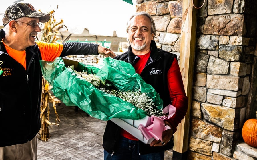 Two men smiling, holding large wrapped bouquet