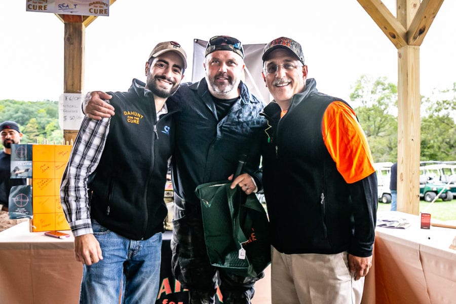 Three men smiling together at outdoor event