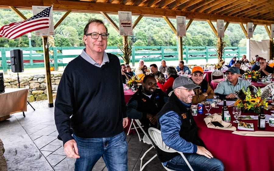 Man near tables under pavilion with American flag
