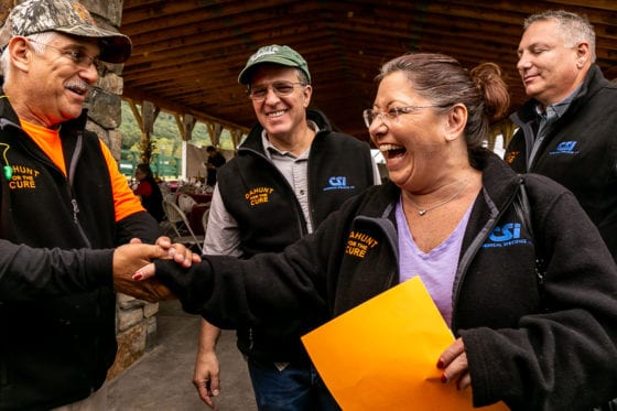 Smiling group exchanging handshake at outdoor pavilion