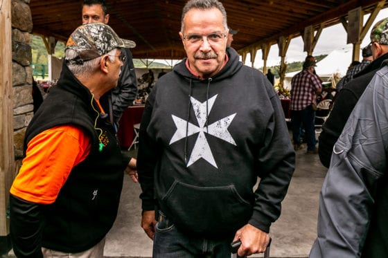 Man wearing Maltese cross hoodie at pavilion