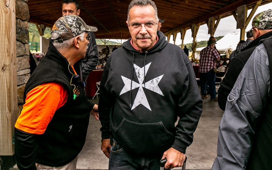 Man wearing Maltese cross hoodie at pavilion
