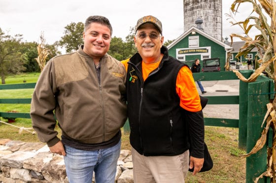 Two smiling men at farm with silo