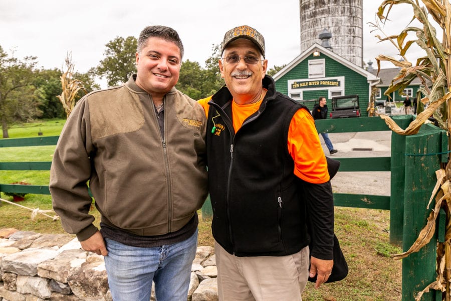 Two smiling men at farm with silo