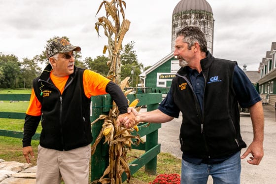 Two men shaking hands near farm silo
