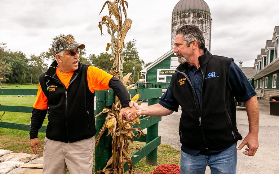 Two men shaking hands near farm silo
