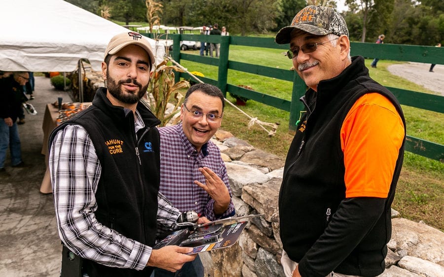 Three men smiling at outdoor harvest festival