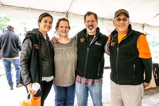Group of four smiling people under event tent