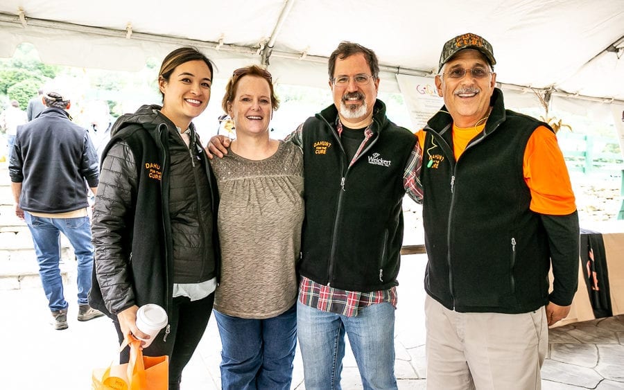 Group of four smiling people under event tent