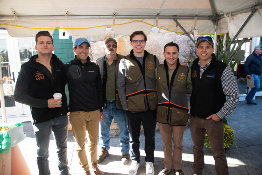 Six men posing under outdoor event tent