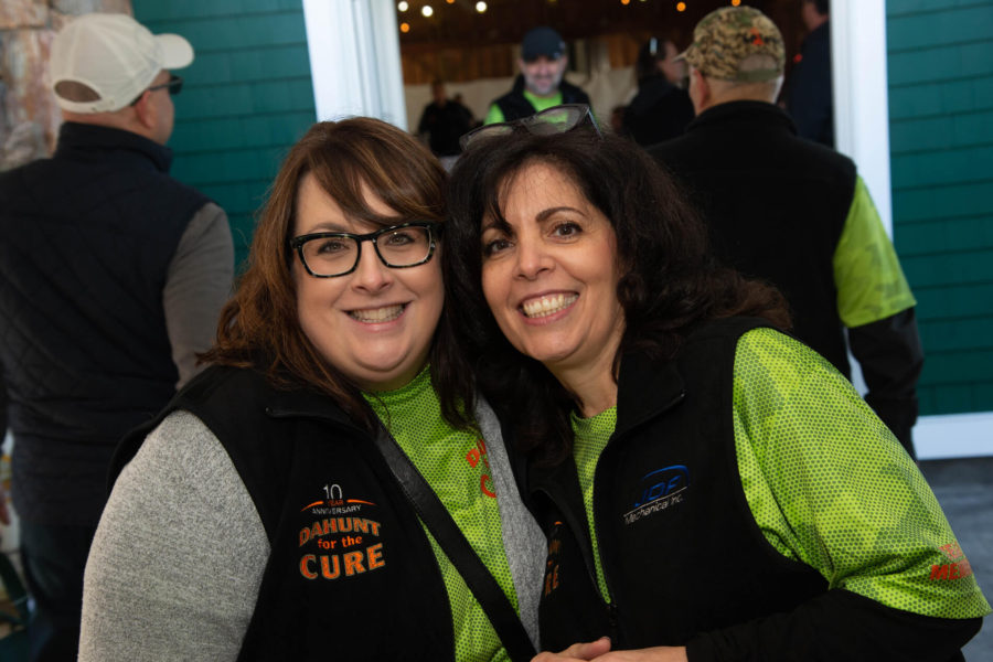 Two smiling women wearing green shirts at event