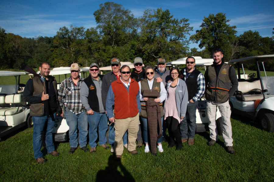 Group of people posing beside golf carts