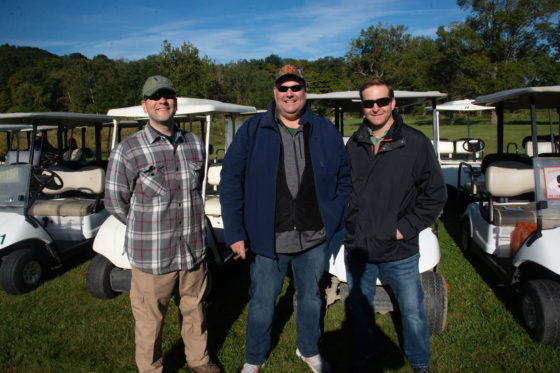 Three men with golf carts on sunny course