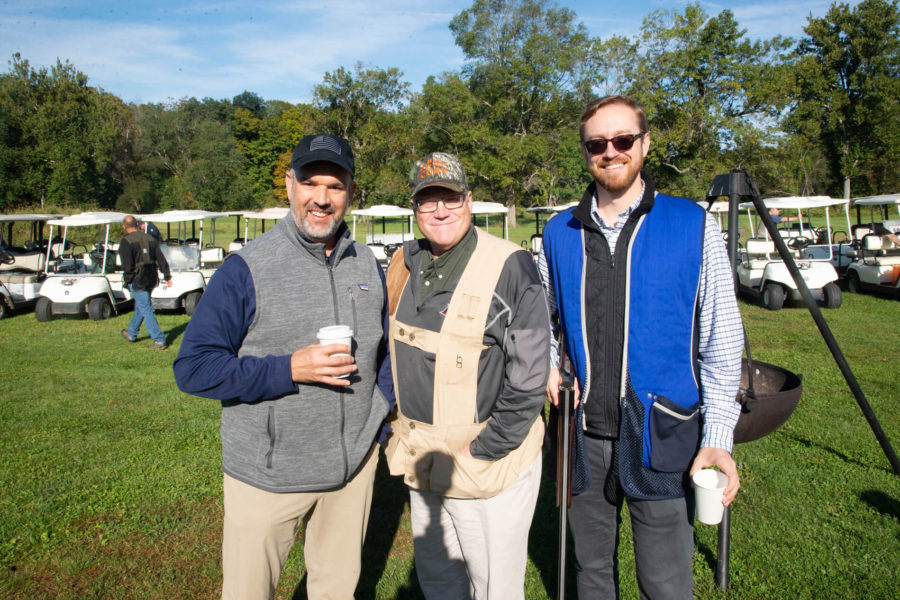 Three men wearing shooting vests outdoors