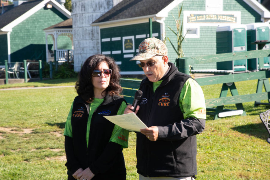 Two speakers outdoors: man reads, woman listens