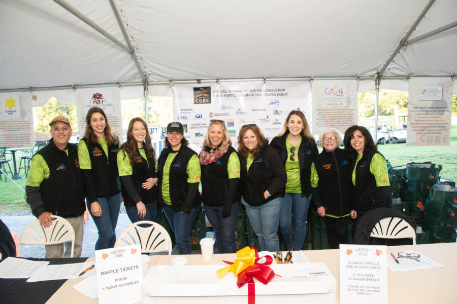 Volunteers at outdoor fundraising tent smiling
