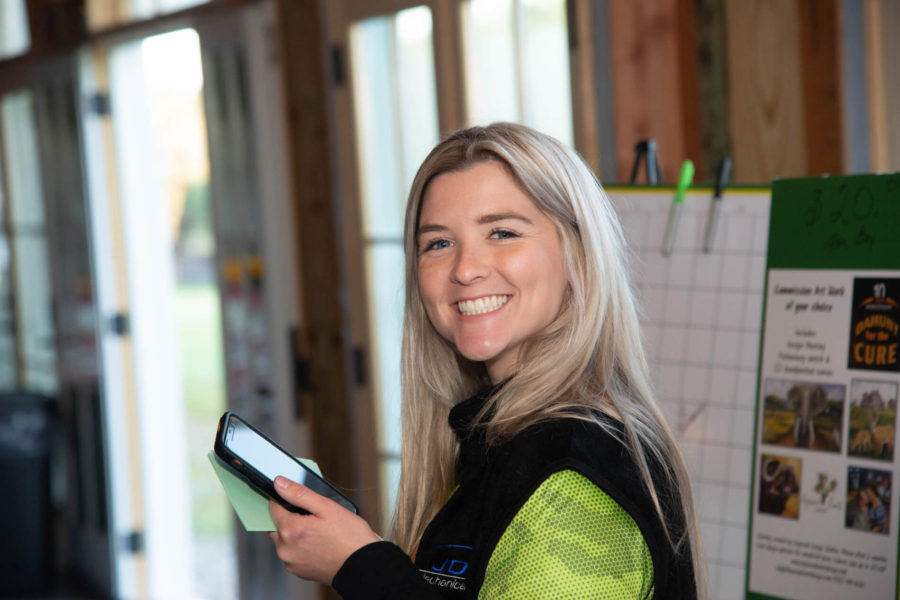 Smiling woman holding smartphone by display board