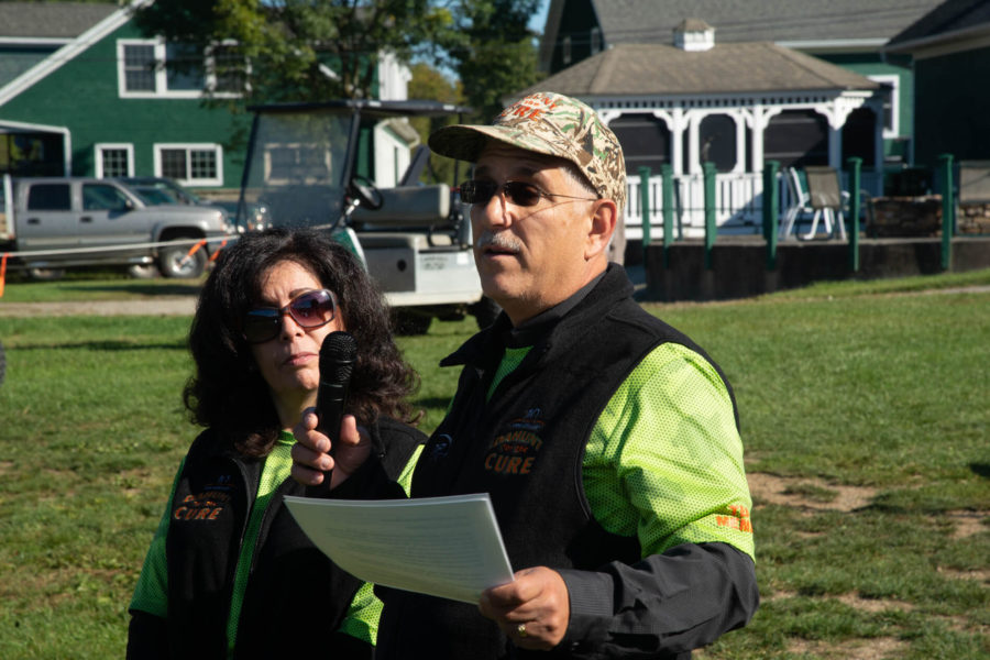 Man speaking into microphone, woman standing beside