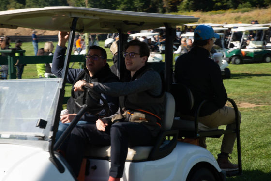 Three men riding in golf cart on course
