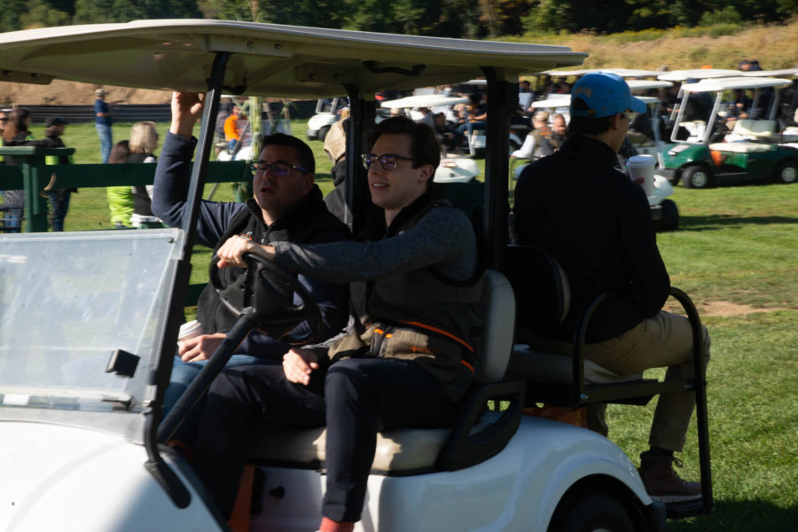 Three men riding in golf cart on course