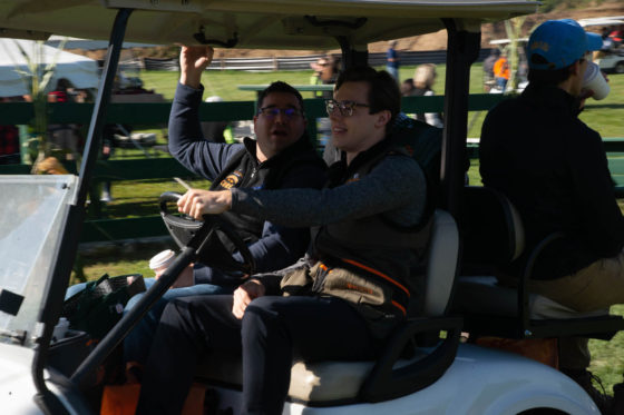 Two people driving a golf cart outdoors
