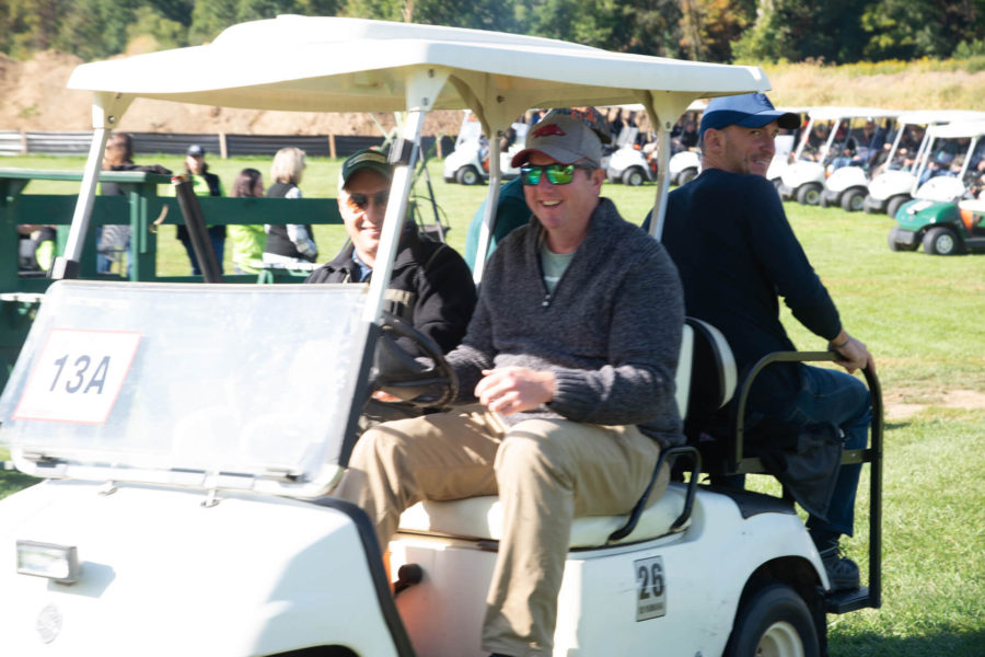 Three golfers riding in a golf cart