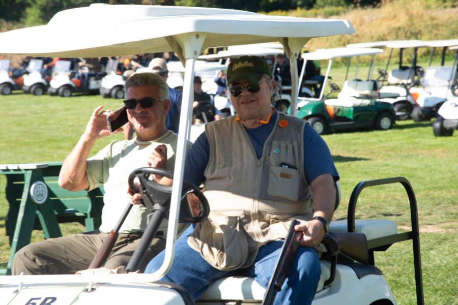 Two men in golf cart, one on phone