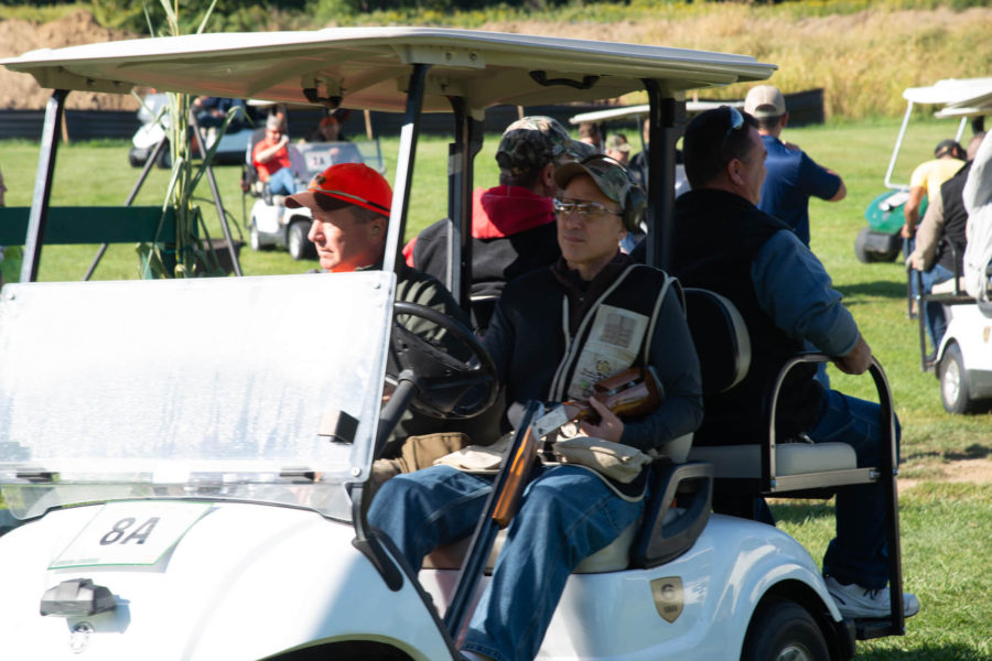 Participants in golf cart holding shotgun