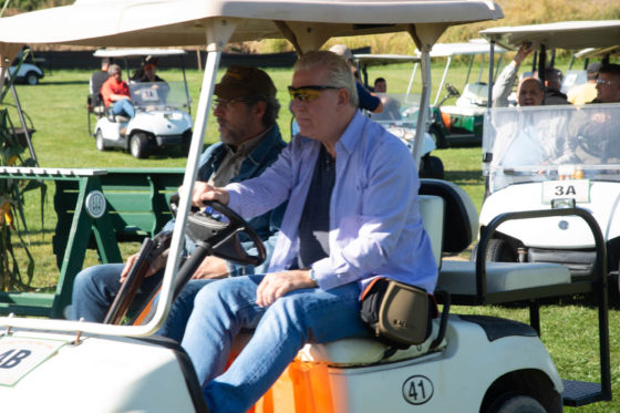 Two men riding in golf cart on course