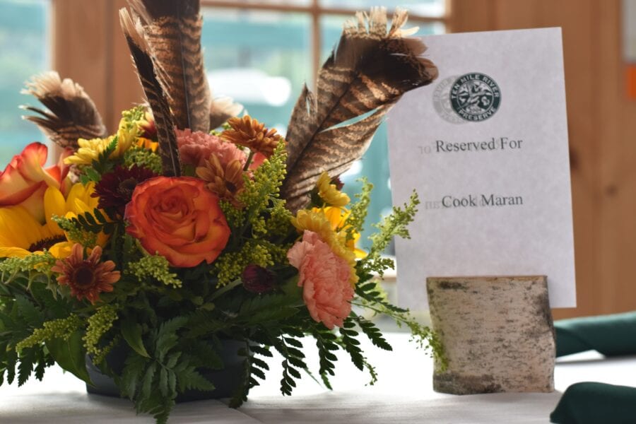 Floral centerpiece with feathers and reserved sign