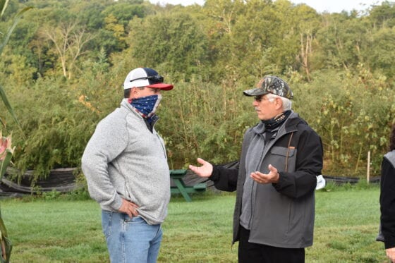 Two men wearing caps and face coverings talking
